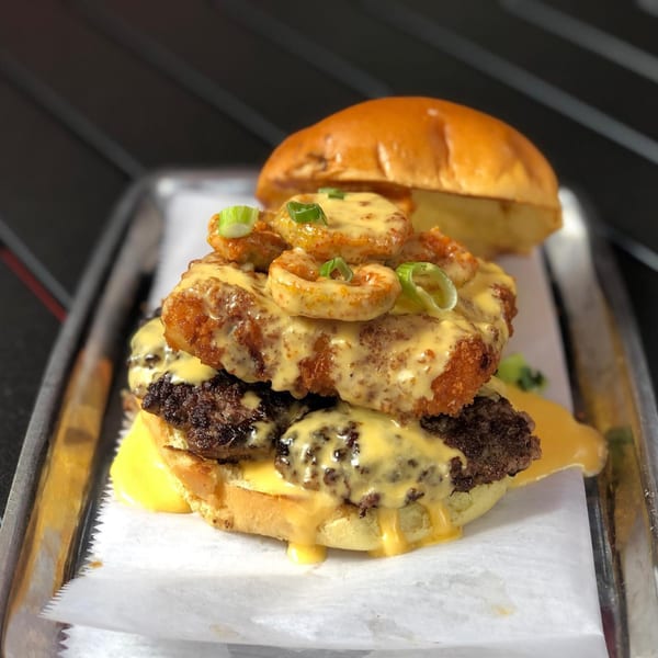Hangar 11 Burgers' double patty burger with fried shrimp, cheese sauce, and green onions.