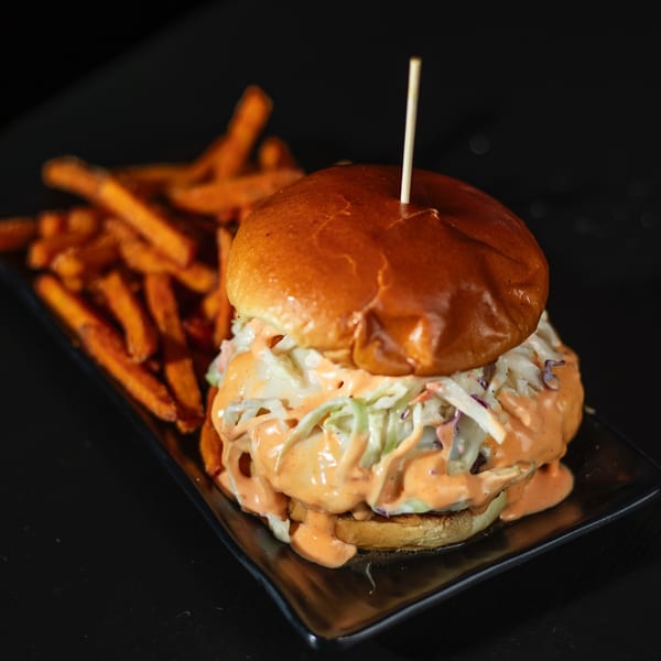 Hangar 11 burger with coleslaw and special sauce, served with sweet potato fries.